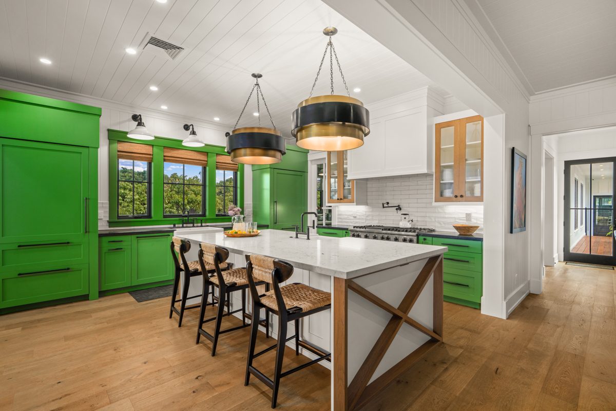 The emerald kitchen with a marble island, bar stools and pendant lights
