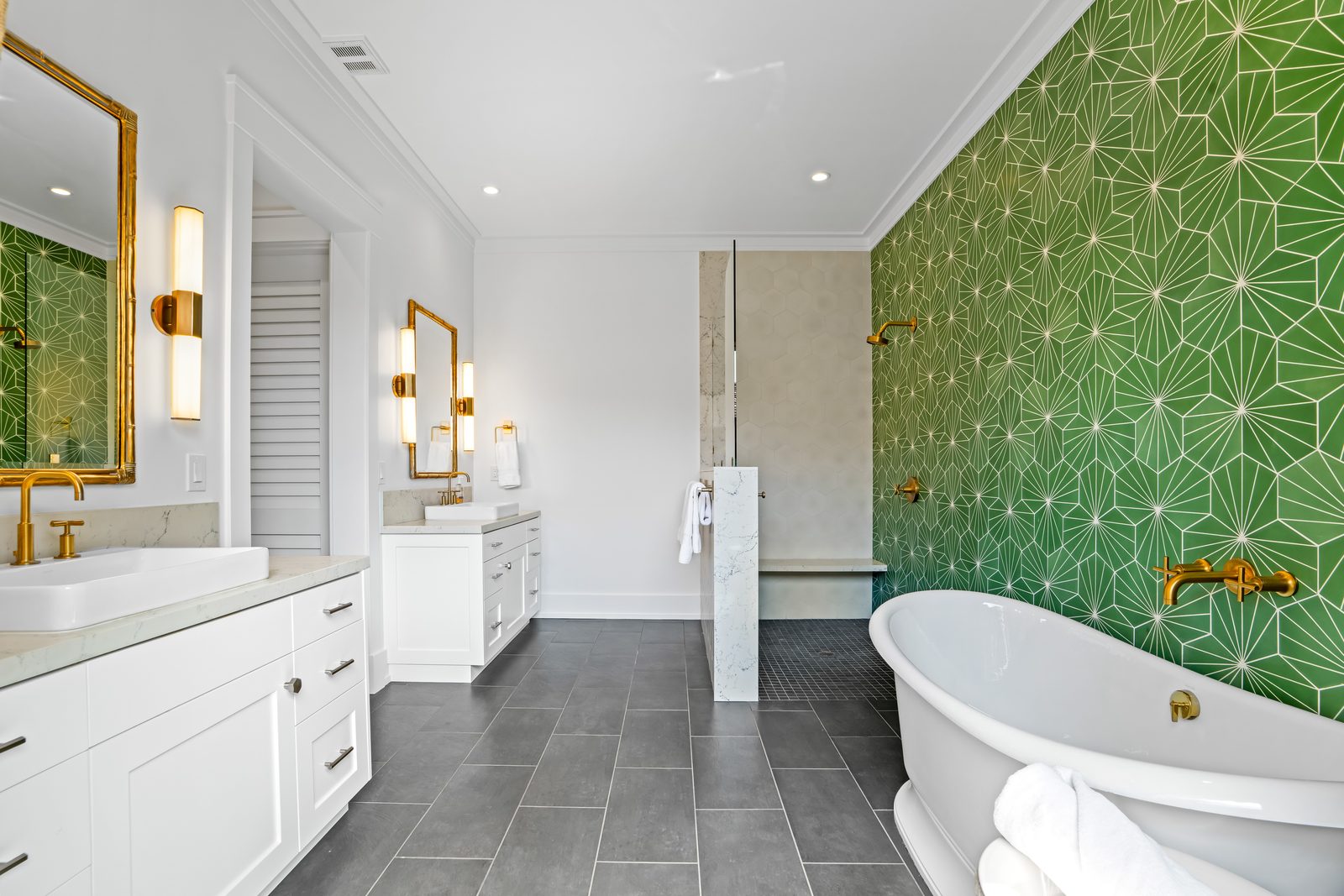 Freestanding soaking tub against the green star tile, with a window to the garden