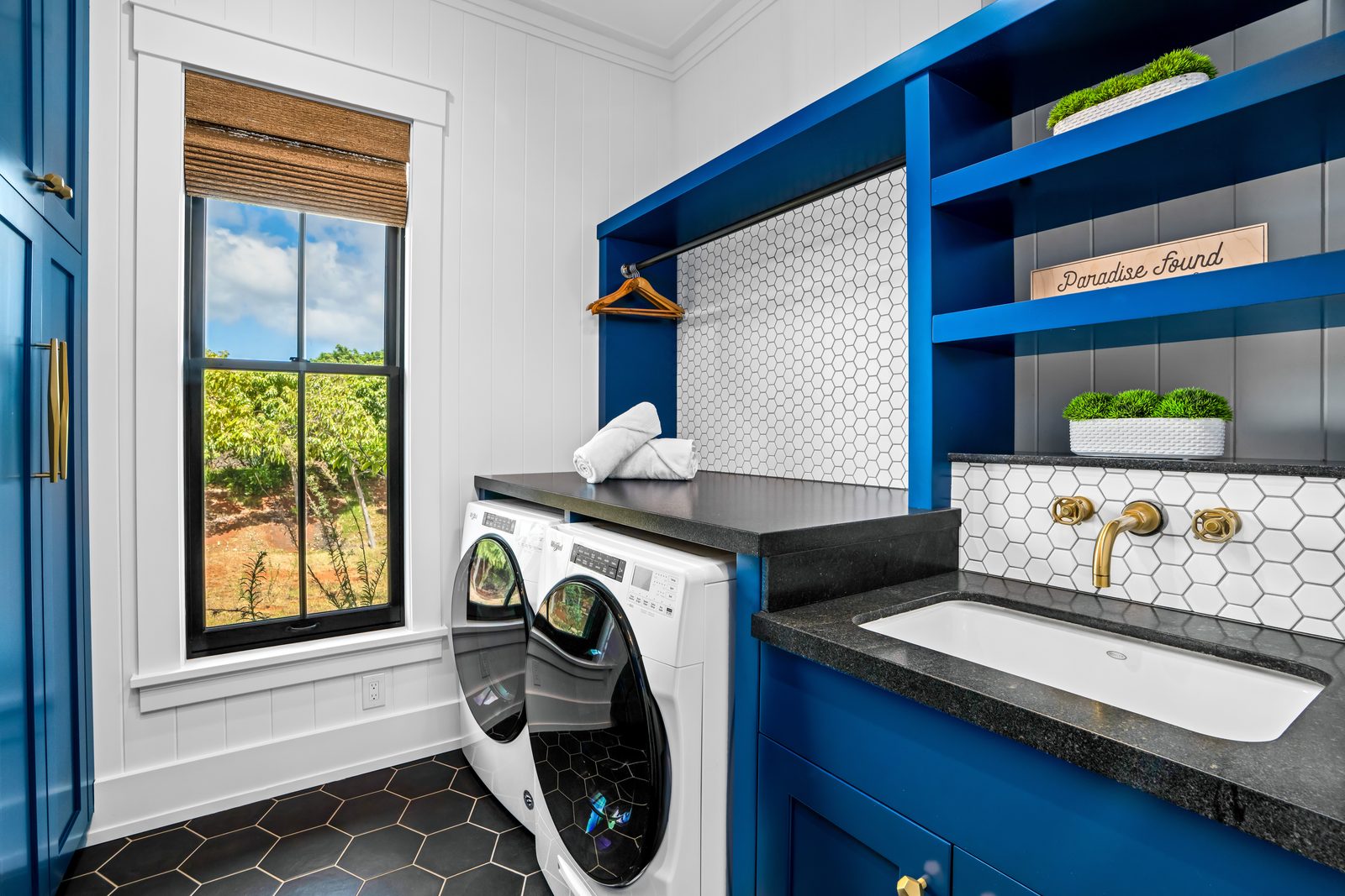 The laundry room with blue cabinetry and a garden window