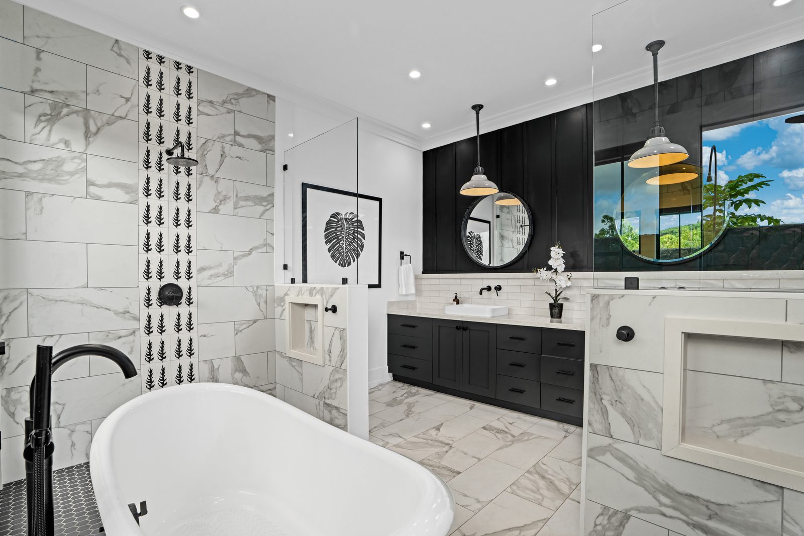 Freestanding soaking tub in the marble bathroom, below black-framed windows