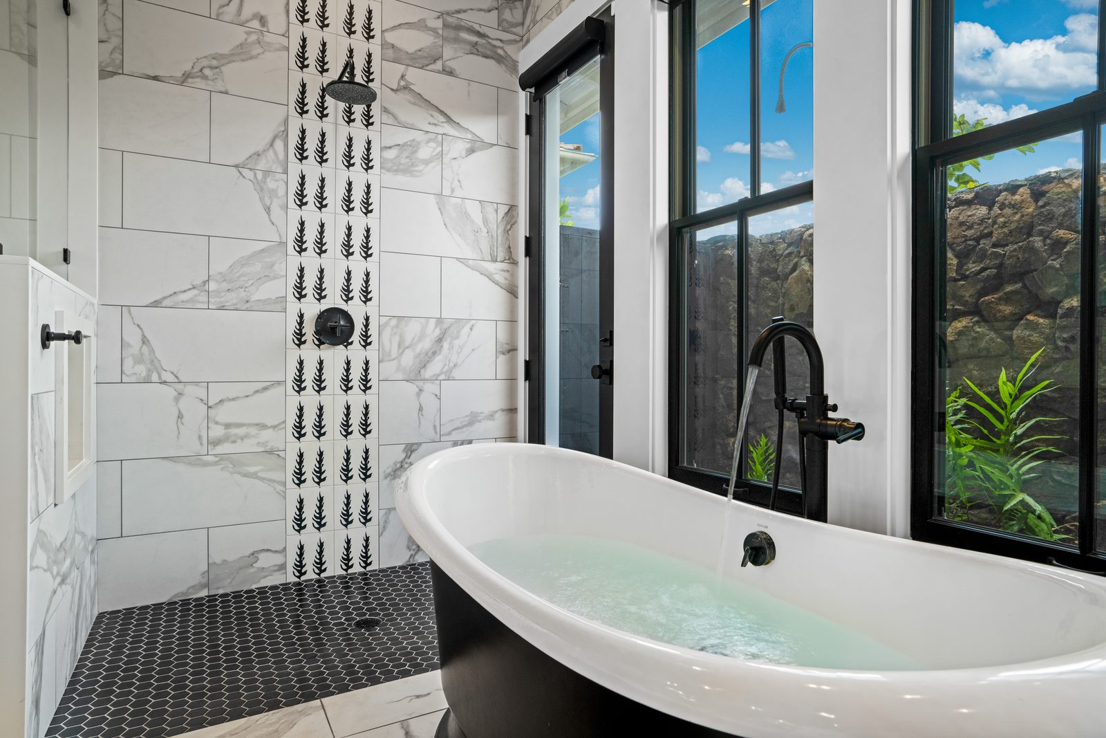 The soaking tub filled, with the lava-rock garden through the window