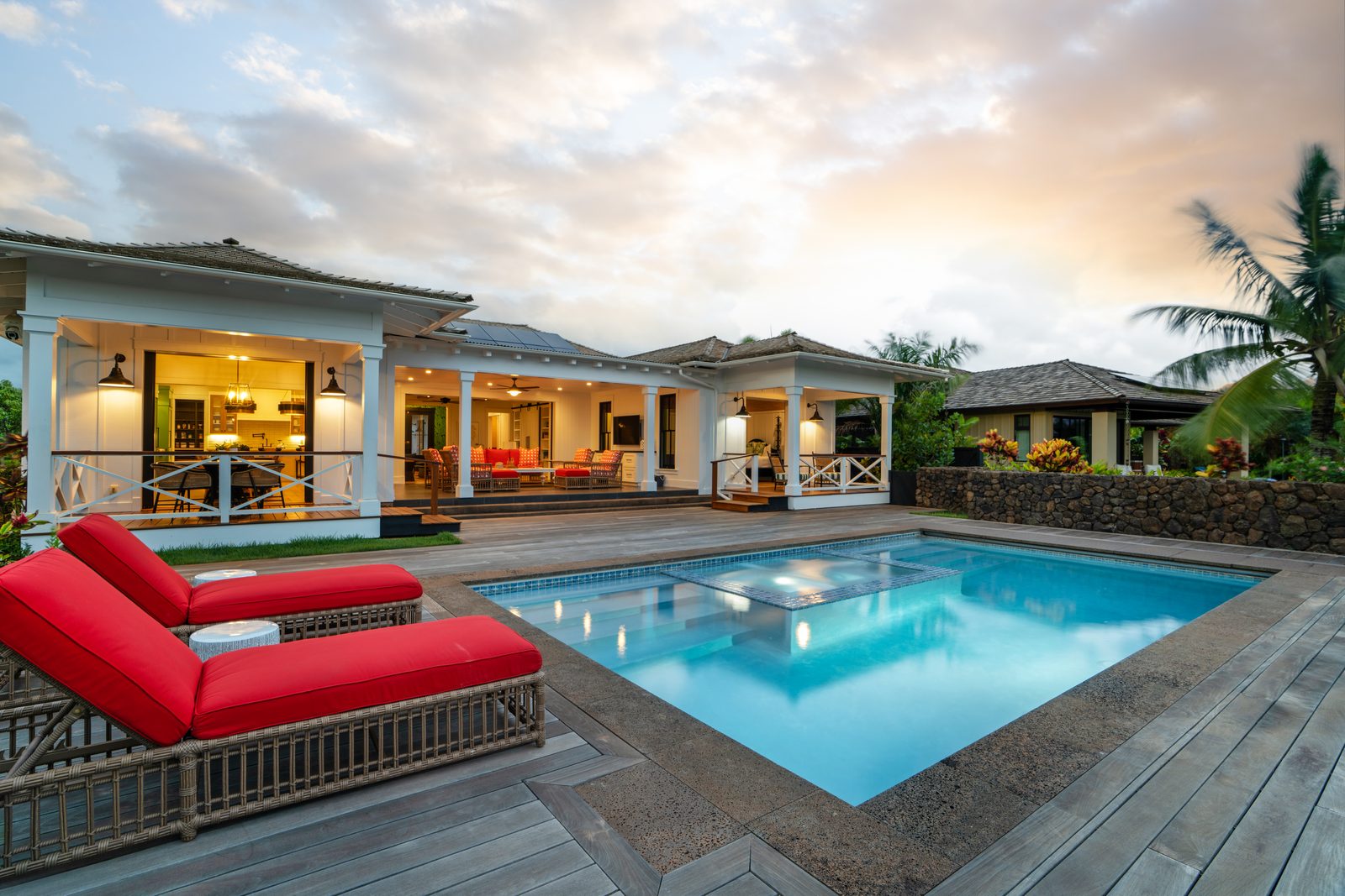 The pool and spa at dusk with the house lit from within